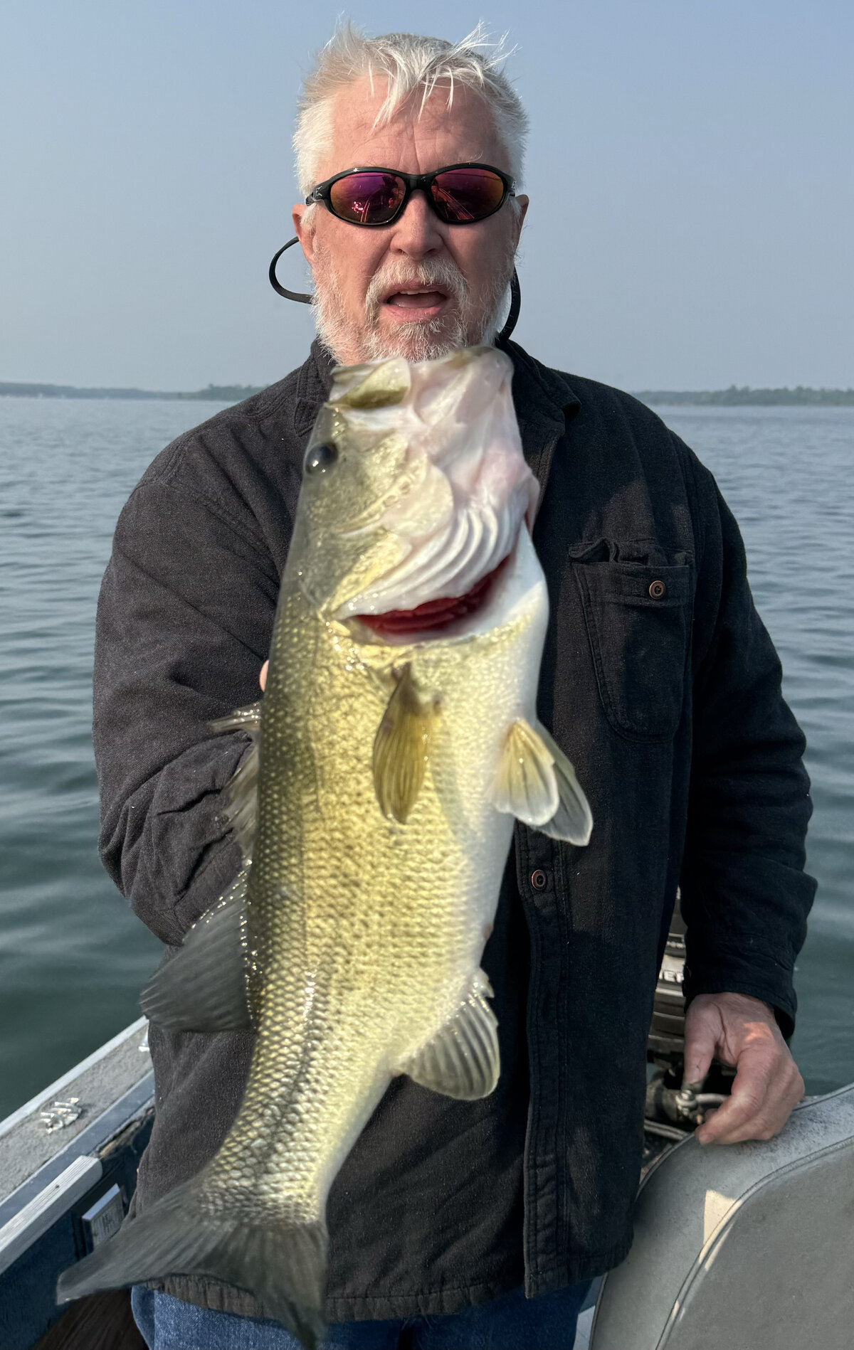 Don Fraim holding a largemouth bass on the water